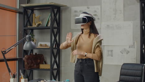 Female-architect-in-office-in-virtual-reality-helmet-uses-gestures-to-manage-a-project-without-leaving-the-office.-Construction-control.-Design-project-of-the-building-and-interior